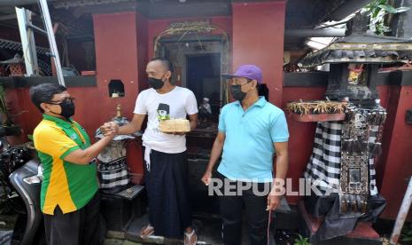 Warga muslim (kiri) memberikan daging kurban kepada warga beragama Hindu pada Hari Raya Idul Adha 1442 H di kawasan Padangsambian, Denpasar, Bali, Selasa (20/7/2021). Daging hewan kurban di wilayah itu dibagikan kepada ribuan masyarakat baik yang beragama Islam maupun non Islam sebagai wujud persatuan dan kerukunan antar umat beragama yang ada di Bali.