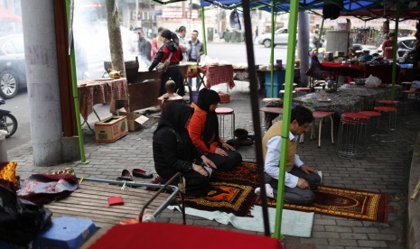 Warga Muslim Uighur Cina menunaikan ibadah di tengah aktivitas siang hari.