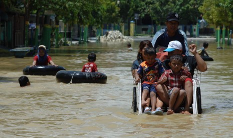 Warga naik becak menerobos banjir di Jalan Imam, Sampang, Jatim, Selasa (27/9).