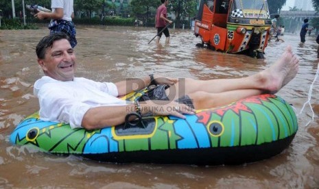   Warga negara asing asal Swiss, Tom Hausler menumpangi perahu karet saat banjir melanda di Jalan MH Thamrin, Jakarta, Kamis (17/1).  (Republika/Aditya Pradana Putra)