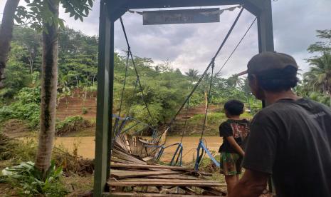 Warga nekat melintasi jembatan gantung rusak untuk menyeberang Sungai Ciseel di Dusun Gunungsari, Desa Ciparay, Kecamatan Cidolog, Kabupaten Ciamis, Kamis (10/11/2022). Rusaknya jembatan itu mengakibatkan ratusan warga di wilayah tersebut terisolasi. 