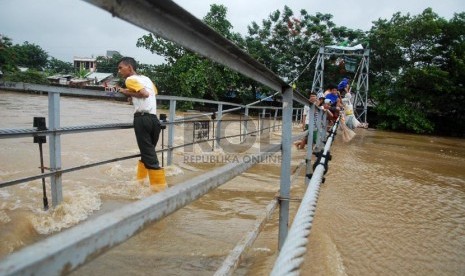 Warga nekat menyeberangi jembatan gantung Jati Pulo yang mulai terendam luapan Banjir Kanal Barat di Kecamatan Pal Merah, Jakarta Barat, Sabtu (18/1).  (Republika/Rakhmawaty La'lang)