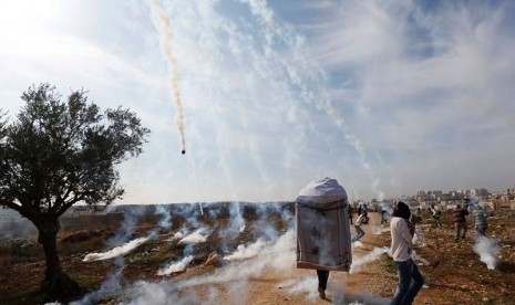 Warga Palestina berhamburan setelah ditembak gas air mata oleh tentara Israel