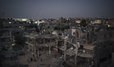 Warga Palestina berjalan di malam hari di sepanjang Jalan Al-Baali, di samping rumah-rumah yang rusak parah akibat serangan udara selama perang 11 hari antara Israel dan Hamas, kelompok militan yang menguasai Gaza, di Beit Hanoun, Jalur Gaza utara, Senin, 31 Mei 2021