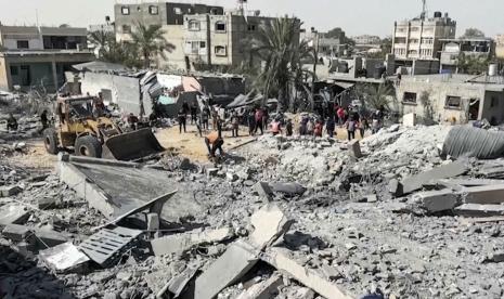 Warga Palestina berkumpul di dekat sebuah bangunan yang hancur akibat serangan udara Israel di kota Khan Younis, Jalur Gaza selatan, Jumat, 25 Oktober 2024.