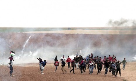 Warga Palestina berlarian saat tentara Israel menembak dengan gas air mata di Jalur Gaza.