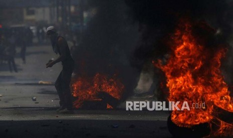 Warga Palestina di antara barikade ban saat bentrok dengan polisi Isreal di pos pemeriksaan Qalandiya di Kota Ramallah, Tepi Barat.