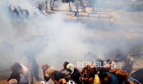 Warga Palestina melaksanakan Shalat Jumat berlarian saat kanister gas air mata yang ditembakkan polisi Israel meledak. Sebelumnya mereka melaksanakan shalat jumat  di jalan menuju di Kota Tua Yerusalem tersebut, Jumat (21/7)