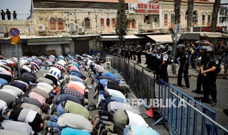 Warga Palestina melaksanakan Shalat Jumat di jalan menuju kompleks Masjid Aqsha yang diblokir polisi Israel di Kota Tua Yerusalem, Jumat (21/7).