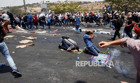 Warga Palestina melaksanakan Shalat Jumat berlarian saat kanister gas air mata yang ditembakkan polisi Israel meledak. Sebelumnya mereka melaksanakan shalat jumat  di jalan menuju di Kota Tua Yerusalem tersebut, Jumat (21/7).