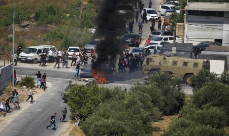 Warga Palestina melemparkan batu ke kendaraan militer Israel selama operasi militer Israel di desa Rujib Tepi Barat, Selasa, 30 Agustus 2022.  Israel telah melatih pasukan militernya untuk mengoperasikan pesawat tak berawak bersenjata selama 