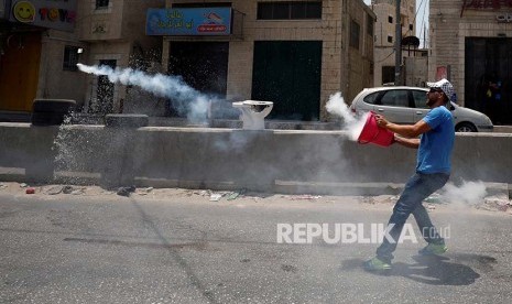 Warga Palestina melemparkan kembali kanister gas airmata ke arah polisi Israel di pos pemeriksaan Qalandiya di Kota Ramallah, Tepi Barat.