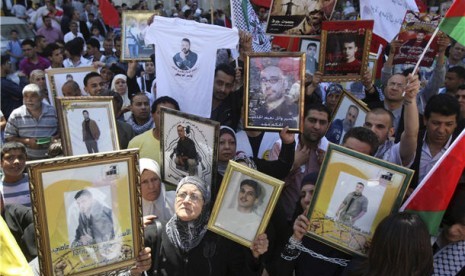 Warga Palestina memegang foto tahanan Palestina di penjara Israel saat marayakan 'Hari Tahanan' di Tepi Barat, Nablus, Selasa (17/4). 