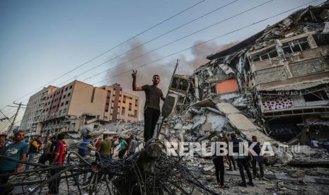 Warga Palestina memeriksa puing-puing menara Al-Shorouq yang hancur setelah serangan Israel di Kota Gaza, Rabu (12/5).