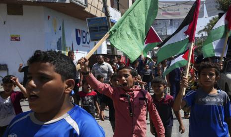 Warga Palestina meneriakkan slogan-slogan sambil mengibarkan bendera nasional mereka.