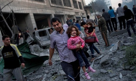 Warga Palestina meninggalkan rumah mereka yang hancur diserang Israel, di dekat lapangan Kota Gaza, Senin (19/11).