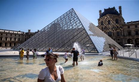 Warga Paris dan wisatawan bersantai di air mancur Piramida Museum Louvre di Paris, Prancis.