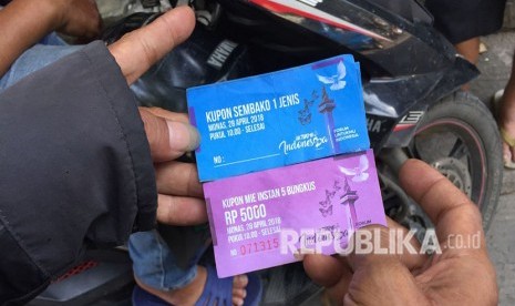 Warga RW 11 Pademangan Barat, menunjukkan kupon yang bisa ditukarkan dengan sembako di acara Untukmu Indonesia.