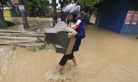 Warga sambil membawa barang melintasi banjir yang melanda desa Pilangsari, Kecamatan Jatibarang, Indramayu, Jawa Barat, Senin (16/3). Banjir akibat jebolnya tanggul sungai Cimanuk merendam sedikitnya 4 kecamatan di Indramayu.