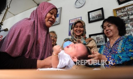  Warga sedang memeriksakan kesehatan anak bayinya di Posyandu Flamboyan, Pinangsia, Jakarta, Kamis (31/3). 