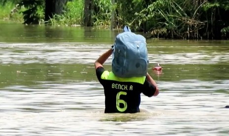 Warga sedsang berjalan melintasi banjir kawasan Bnadung Selatan