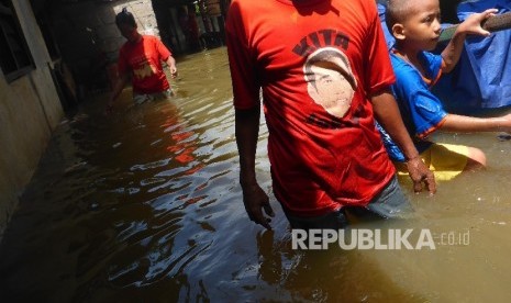 Warga sekitar Kali Strada kawasan Pejaten melintasi genangan banjir yang merendam rumahnya setelah hujan deras yang melanda Jakarta Selatan, Kamis (21/4). (Republika/ Yogi Ardhi)