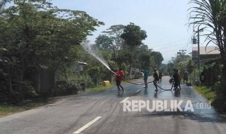 Warga sekitaran kaki Gunung Merapi menyirami jalan-jalan yang sempat tertutup abu erupsi, Jum'at (11/5).  Erupsi freatik sendiri terjadi sekitar pukul 07.00, berlangsung sekitar lima menit dan disertai gempa.