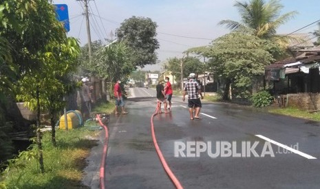 Warga sekitaran kaki Gunung Merapi menyirami jalan-jalan yang sempat tertutup abu erupsi, Jum'at (11/5).  Erupsi freatik sendiri terjadi sekitar pukul 07.00, berlangsung sekitar lima menit dan disertai gempa.