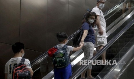 Kondisi WNI Terinfeksi Corona di Singapura Stabil. Warga Singapura memakai masker saat menaiki eskalator di dalam stasiun kereta api di Singapura. 