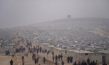 Warga Suriah berjalan di sebuah kamp pengungsi untuk orang-orang terlantar yang dikelola oleh Bulan Sabit Merah Turki di distrik Sarmada, utara kota Idlib, Suriah, Jumat, 26 November 2021.