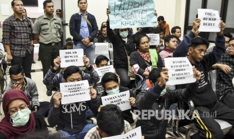 Warga Tamansari korban penggusuran bersama aktivis yang tergabung dalam Tamansari Melawan memegang poster saat menyaksikan jalannya persidangan di Pengadilan Tata Usaha Negara (PTUN) Badung, Jalan Diponegoro, Kota Bandung, Kamis (19/12).