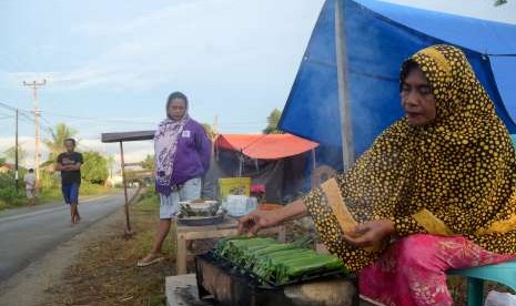 Warga terdampak gempa dan tsunami Palu-Donggala menjual penganan di kawasan pengungsian hunian sementara yang dibangun warga di Biromaru, Kabupaten Sigi, Sulawesi Tengah, Sabtu (13/10).