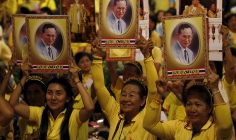 Warga Thailand membawa potret Raja Bhumibol Adulyadej.