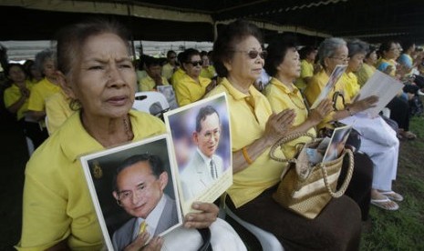 Warga Thailand memegang foto Raja Bhumibol Adulyadejsaat do bersama di luar Istana untuk merayakan ulang tahun ke-70 raja, Kamis, 9 Juni 2016.