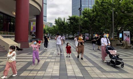 Warga yang mengenakan masker wajah mengunjungi jalan perbelanjaan populer di Shanghai, Cina, Ahad, 29 Mei 2022. Pembukaan kembali sebagian toko dan kantor di Beijing disambut oleh penduduk yang lelah dan pemilik toko yang berjuang untuk hidup kembali normal.