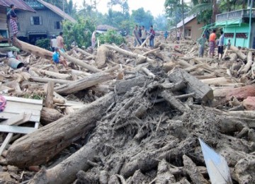 Warga melihat kayu gelondongan ilegal yang berserakan setelah hanyut dibawa banjir bandang di Kecamatan Tangse, Kabupaten Pidie, NAD, Senin (14/3). Perambahan hutan secara membabi buta sejak lima tahun belakangan ini menyebabkan perkampungan di bawah pegun