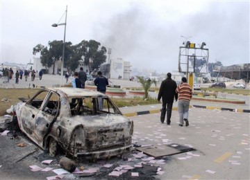 Warga melintas bangkai mobil yang terbakar di jalanan Benghazi