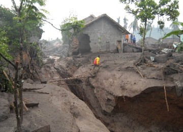 Warga melintas jembatan darurat diatas aliran baru sungai yang terbentuk akibat terjangan lahar hujan di Dusun Gempol, Jumoyo, Salam, Magelang, Selasa (4/1). Belum ada laporan korban jiwa dalam bencana yang menghantam perumahan penduduk.