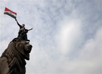 Warga Mesir mengibarkan bendera negaranya di atas patung.