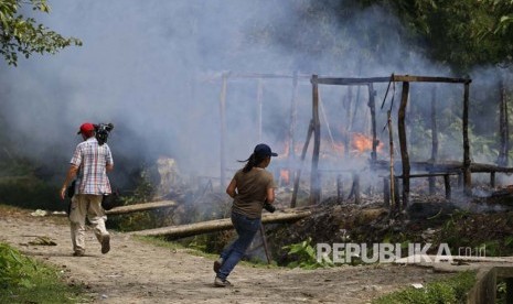  Wartawan berjalan di dekat rumah-rumah yang terbakar di desa Gawdu Thara di kota Maungdaw, Negara Bagian Rakhine, Myanmar barat. Militer Myanmar disebut tak melaporkan kasus pembantaian Rohingya secara utuh. Ilustrasi. 