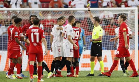 Wasit Aleksei Kulbakov mengeluarkan kartu kuning kepada pemain Sevilla Diego Carlos (tengah) dalam pertandingan Liga Champions Grup G antara Sevilla FC dan RB Salzburg di Stadion Sanchez Pizjuan, Spanyol. 