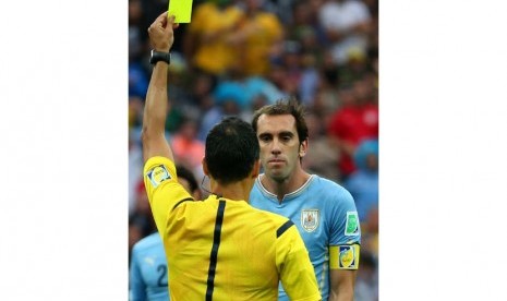 Wasit Carlos Velasco Carballo Spanyol menunjukkan kartu kuning kepada Diego Godin dari Uruguay selama dipertandingan babak penyisihan antara Uruguay dan Inggris di Arena Corinthians di Sao Paulo, Brasil, Kamis (19/6).   (EPA/ Diego Azubel).