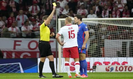 Wasit Daniel Siebert menunjukkan kartu kuning kepada Harry Maguire dari Inggris, kanan, dan Kamil Glik dari Polandia selama pertandingan sepak bola kualifikasi grup I Piala Dunia 2022 antara Polandia dan Inggris, di stadion Narodowy di Warsawa, Rabu, 8 September 2021