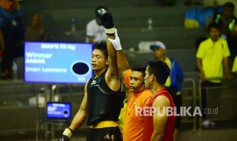 Wasit mengangkat tangan Iman Lesmana asal Jabar (kanan) usai bertarung dengan Syafrizal asal Aceh (kiri) pada petarungan Wushu kelas Sanshou 70 kg putra babak penyisihan, dengan , di Gor Pajajaran, Kota Bandung, Senin (19/9)