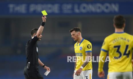 Wasit Stuart Attwell (kiri) menunjukkan kartu kuning kepada pemain Brighton Ben White (tengah) pada pertandingan sepak bola Liga Utama Inggris antara Chelsea dan Brighton dan Hove Albion di Stadion Stamford Bridge di London, Rabu (21/4) dini hari WIB.