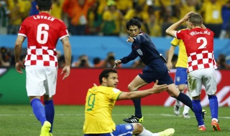 Wasit Yuichi Nishimura (tengah) dari Jepang, untuk memberikan hukuman selama Piala Dunia 2014 pertandingan pembukaan antara Brasil dan Kroasia di arena Corinthians di Sao Paulo 13 Juni 2014.