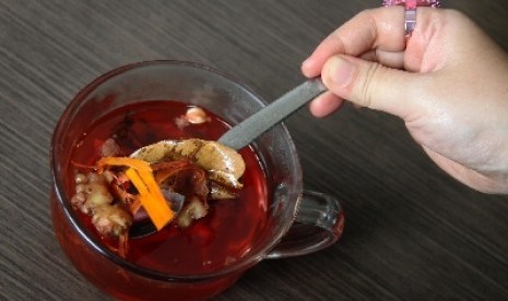 Wedang uwuh, minuman tradisional yang terbuat dari aneka rempah, dibagikan gratis oleh salah seorang pedagang angkringan di Surabaya, Jawa Timur.