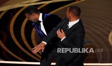 Will Smith (kanan) memukul presenter Chris Rock di atas panggung saat mempersembahkan penghargaan untuk film dokumenter terbaik di Oscar pada Ahad 27 Maret 2022, di Dolby Theatre di Los Angeles.