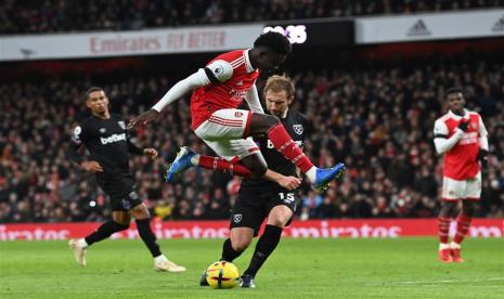 Winger Arsenal Bukayo Saka (kiri) beraksi menghadapi West Ham United pada lanjutan Liga Primer Inggris 2022 di Stadion Emrates, London, Selasa (27/12/2022). Saka mencetak satu gol dalam laga yang dimenangkan Arsenal dengan skor 3-1 itu.