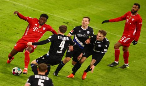 Winger Bayern Muenchen Alphonso Davies (kiri) dijaga sejumlah pemain Arminia Bielefeld dalam pertandingan Bundesliga Jerman. Davies mencetak gol penyama kedudukan 3-3.  